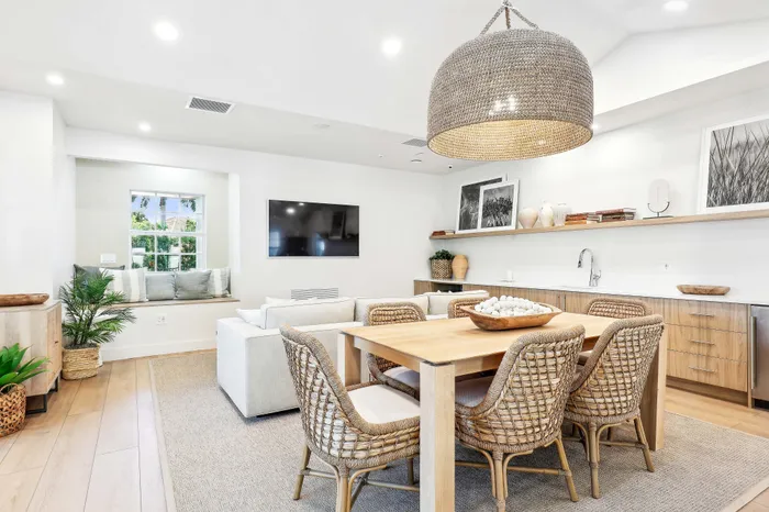 Inviting open-concept living area with elegant decor, featuring a cozy dining space, plush seating, and modern amenities under a chic woven chandelier.