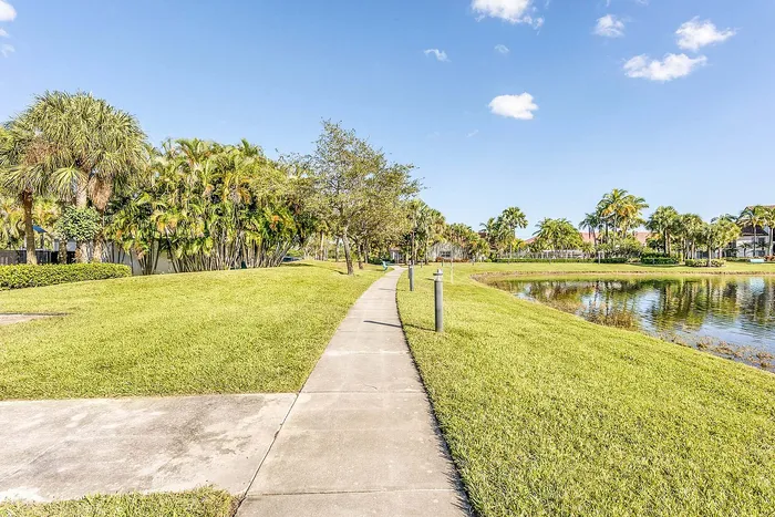 Serene walkway lined with lush palm trees and a tranquil pond, perfect for relaxing strolls in a tropical setting.