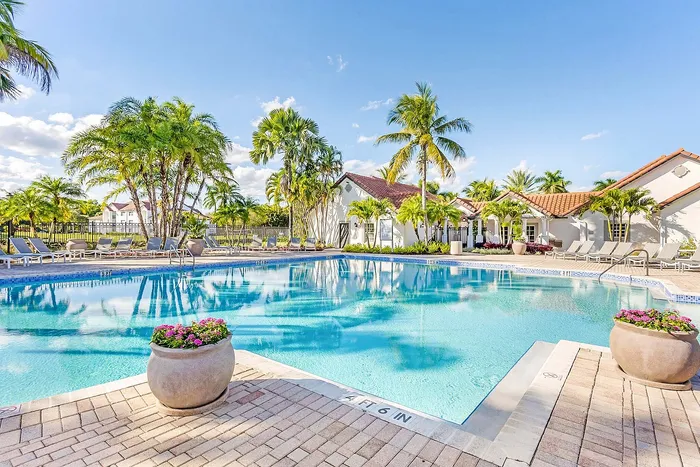 Inviting pool area surrounded by palm trees and sun loungers, showcasing a serene tropical atmosphere and elegant architecture.
