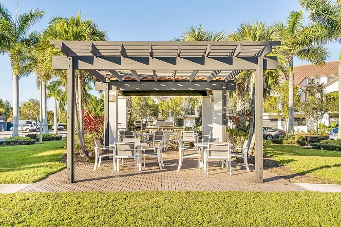 Inviting outdoor patio area with stylish pergola and comfortable seating, surrounded by lush palm trees and vibrant greenery.