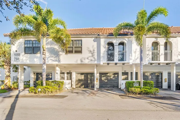 Charming townhouse exterior with Mediterranean-style balconies and vibrant palm trees against a clear blue sky.