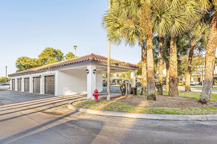 Charming outdoor view featuring a row of garages with terra-cotta roof and surrounded by lush palm trees, exemplifying a serene and inviting ambiance.