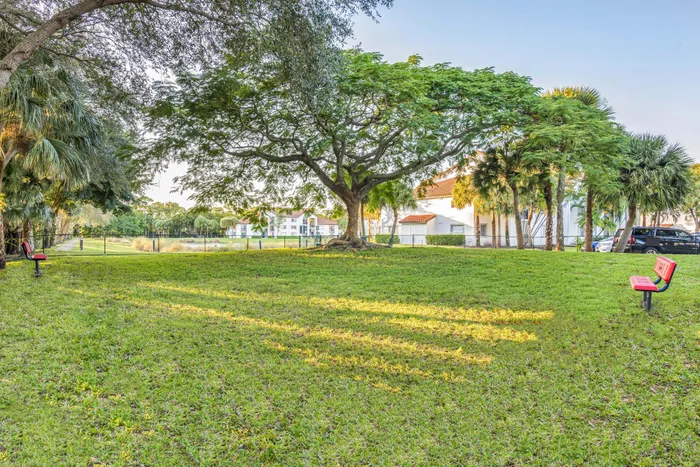 Charming park view featuring lush greenery, majestic trees, and inviting benches near a serene apartment complex.