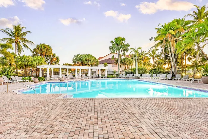 Luxurious outdoor pool area surrounded by lush palm trees and elegant lounge chairs, perfect for relaxing under the sun.