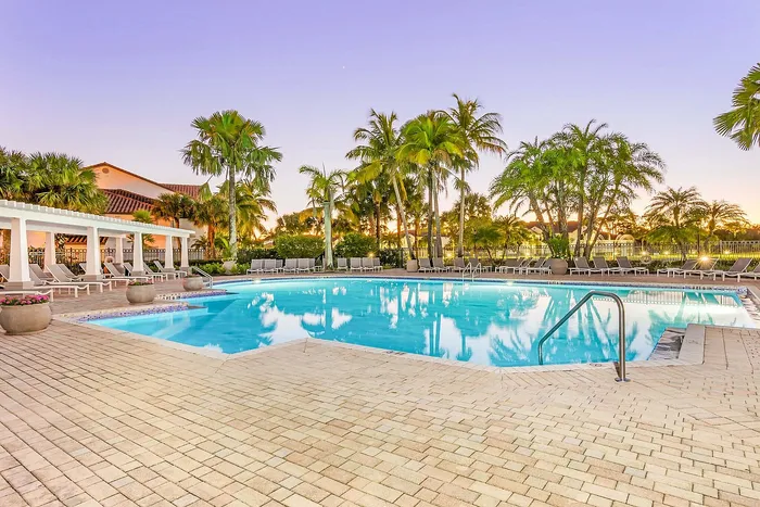 Luxurious swimming pool surrounded by palm trees and elegant loungers, perfect for relaxation and leisure.