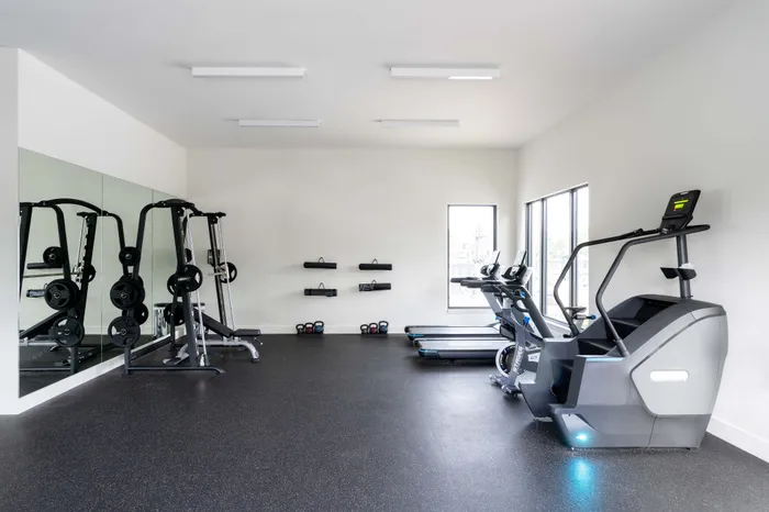 Modern fitness center with state-of-the-art exercise equipment, including treadmills, weight machines, and a sleek mirrored wall for an invigorating workout experience.