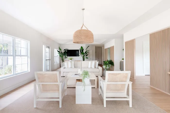 Bright and airy living room showcasing elegant white furniture, large windows, and lush green plants for a serene ambiance.