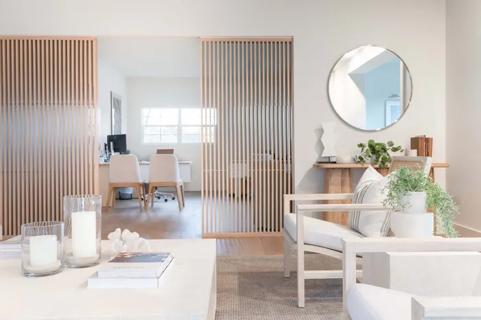 Bright, open-concept living space with elegant wooden screen divider, cozy seating area, and stylish desk, perfect for modern living.