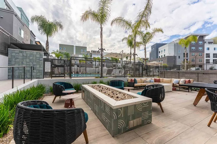 Chic outdoor lounge space with stylish seating, a modern fire pit, and lush palm trees, perfectly complementing a luxurious pool area.