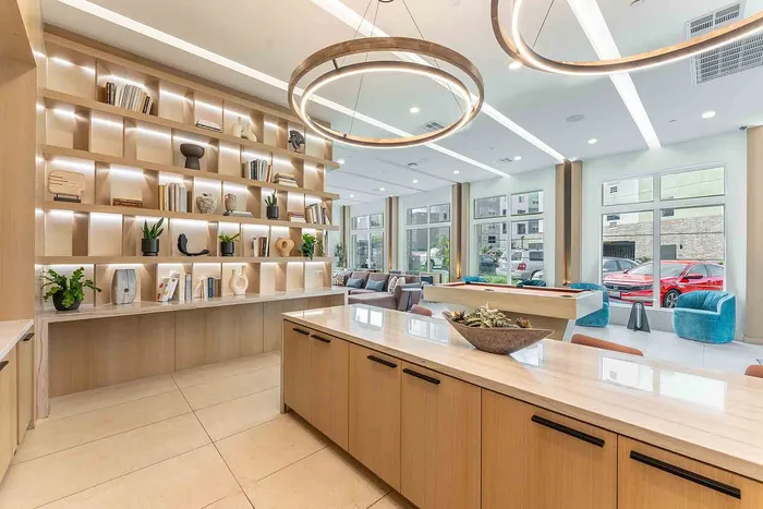 Clubroom kitchen with stylish open shelves, chic decor, and expansive windows inviting natural light.