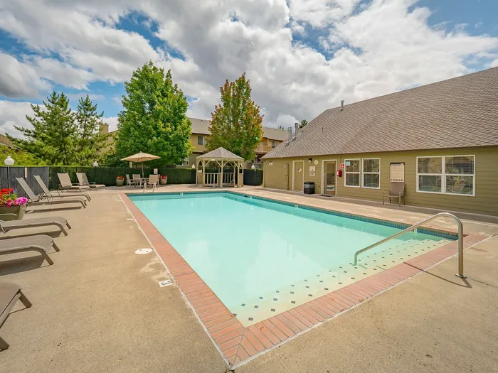 Inviting outdoor pool area with relaxing lounge chairs, surrounded by lush greenery and a charming gazebo.