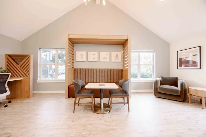 Modern and inviting apartment space featuring a cozy seating area with elegant wood accents, plush armchairs, and ample natural light.