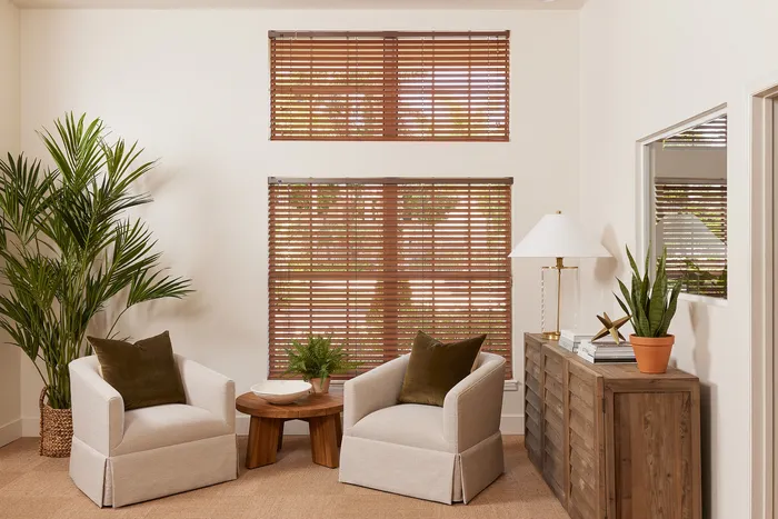 Elegant living room with cozy beige armchairs, lush green plants, and warm wooden accents creating a serene ambiance.