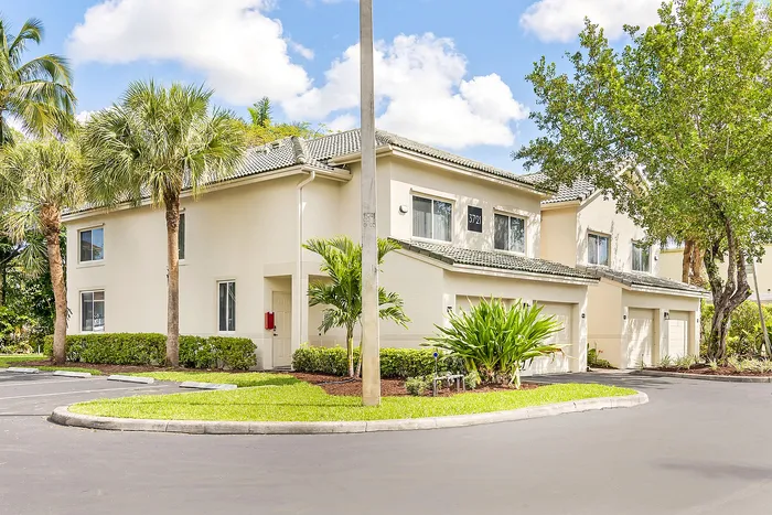 Charming residential exterior view showcasing modern townhouses surrounded by lush greenery and palm trees.