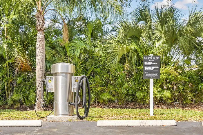 Modern car care center with a sleek vacuum station set against lush tropical greenery.