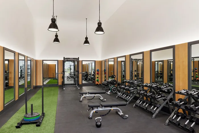 Modern fitness center with a sleek design, featuring state-of-the-art gym equipment, mirrored walls, and vibrant exercise area.