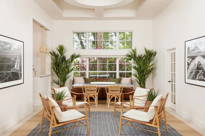 Bright and inviting living room with elegant wooden furniture, lush greenery, and large windows offering a serene garden view.