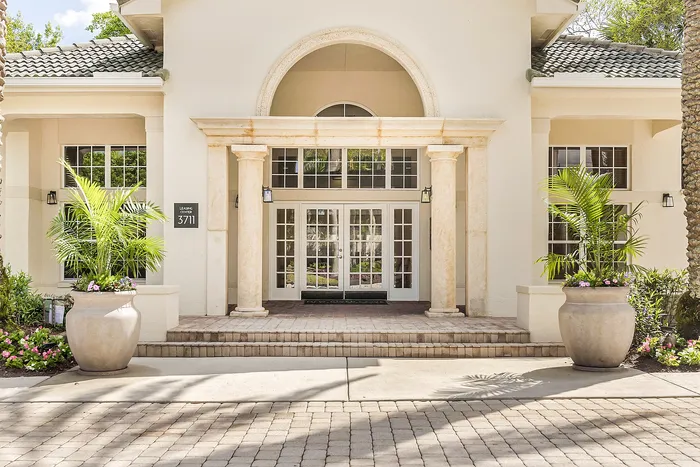 Elegant leasing center entrance with grand columns and lush greenery, welcoming you to a luxurious community.