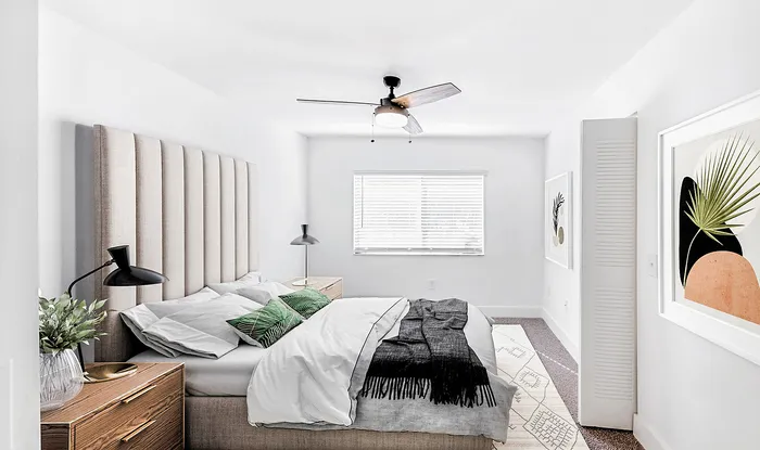 Bright and stylish bedroom featuring a modern ceiling fan, elegant artwork, and a cozy bed with plush pillows.