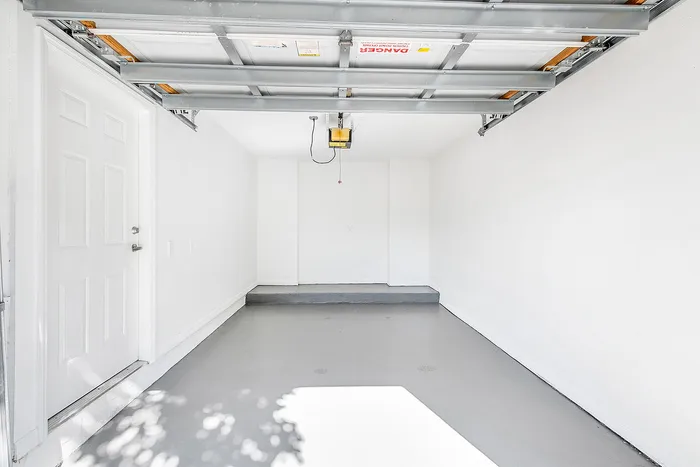 Modern, single-car garage with clean white walls and sleek gray flooring, offering ample space and functionality.