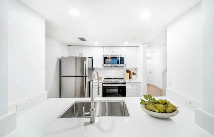 Sleek modern kitchen featuring stainless steel appliances, elegant white cabinetry, and a spacious countertop with a stylish sink.