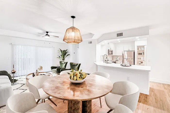 Bright and elegant open-concept living area with modern kitchen, cozy seating, and a rustic dining table, perfect for entertaining.