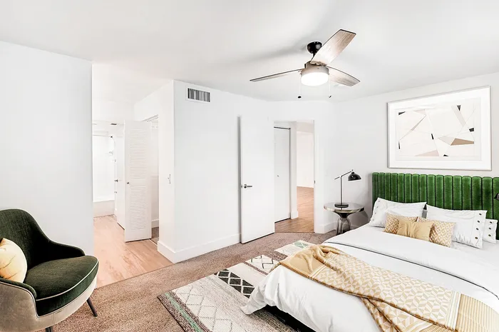 Bright and inviting bedroom with stylish green headboard, cozy armchair, and modern decor, offering a peaceful retreat.