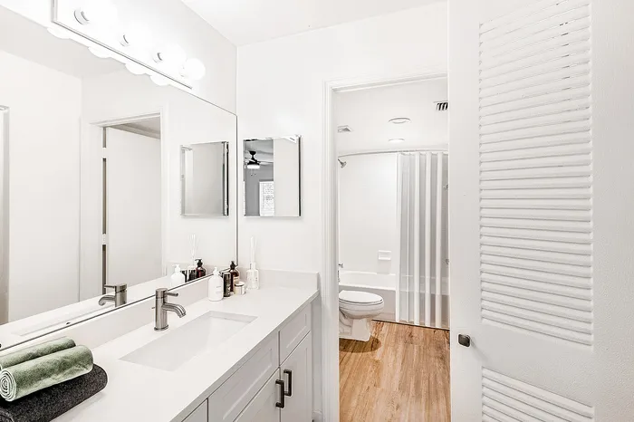 Bright and modern bathroom with elegant fixtures, spacious countertop, and luxurious wooden flooring.