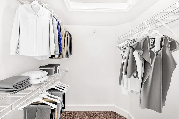 Spacious and organized walk-in closet with neatly hung clothes, shelving, and ample storage space.