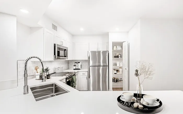Modern kitchen with sleek stainless steel appliances, elegant white cabinetry, and a cozy coffee nook.