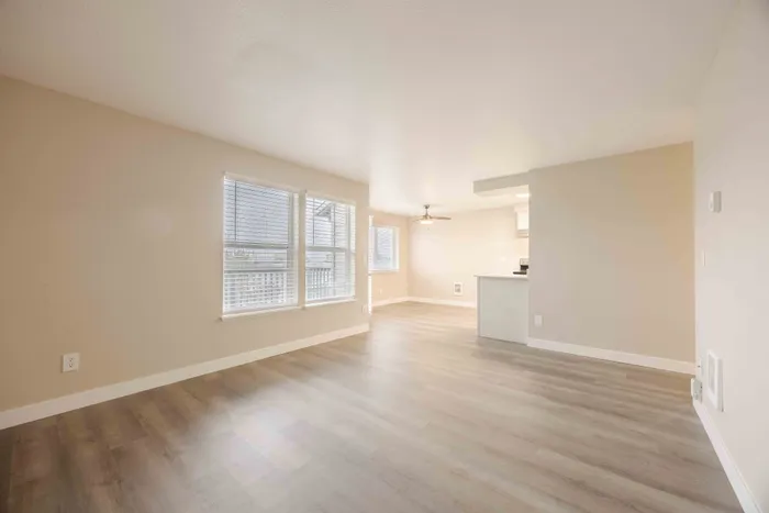 Bright and airy open-concept living space featuring modern flooring, large windows, and a sleek kitchen with white cabinetry.