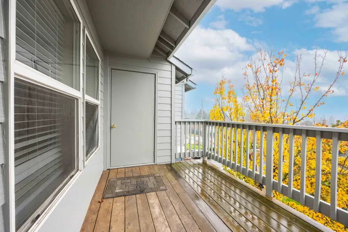 Charming apartment balcony with wooden flooring and vibrant autumn views, perfect for relaxing and enjoying nature.