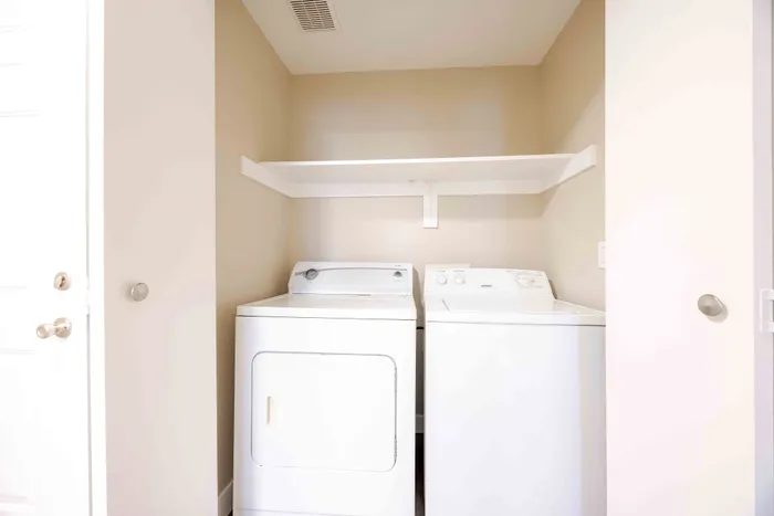 Modern utility area with sleek white washer and dryer, complemented by built-in shelving for optimal storage.