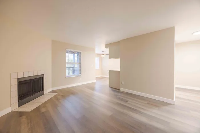 Bright and welcoming living area with elegant laminate flooring, a cozy fireplace, and ample natural light from large windows.