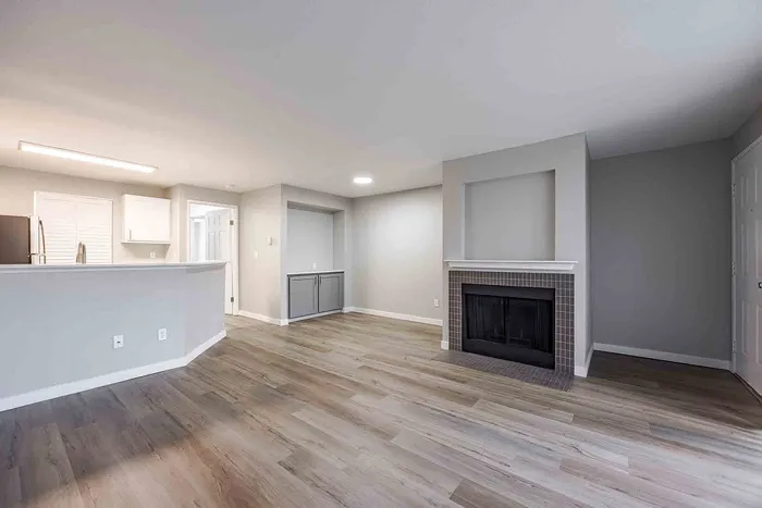 Elegant open-plan living space with a cozy fireplace and modern kitchen, featuring sleek cabinetry and warm wooden floors.