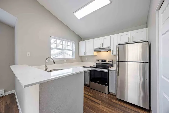 Modern kitchen with sleek stainless steel appliances, white cabinetry, and a bright window view, perfect for culinary enthusiasts.