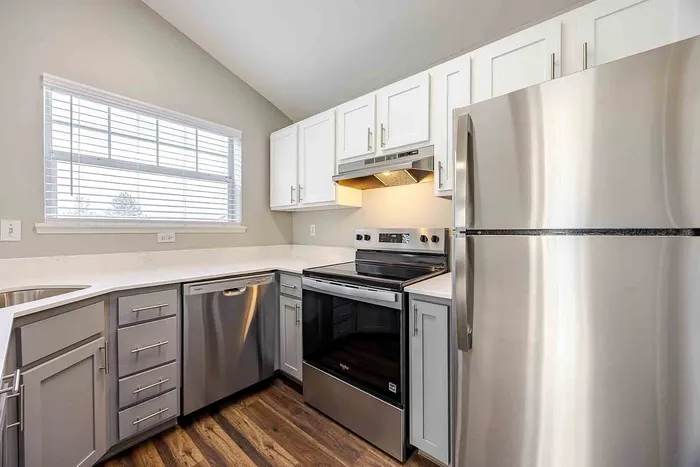 Modern kitchen with sleek stainless steel appliances, elegant white cabinetry, and natural light streaming through a large window.