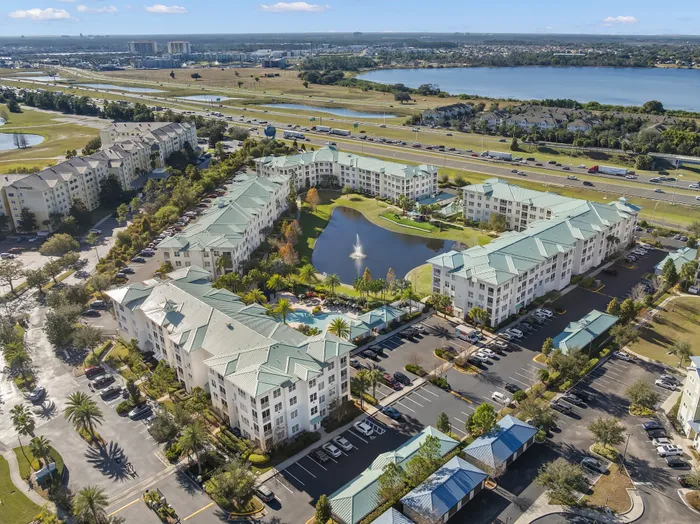 Charming apartment complex with lush landscaping, a serene centerpiece pond, and a refreshing pool, offering scenic views and modern living.