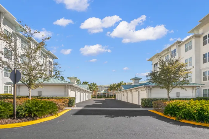 Gorgeous residential complex with a clean pathway leading through lush landscaping and modern architecture under a bright blue sky.