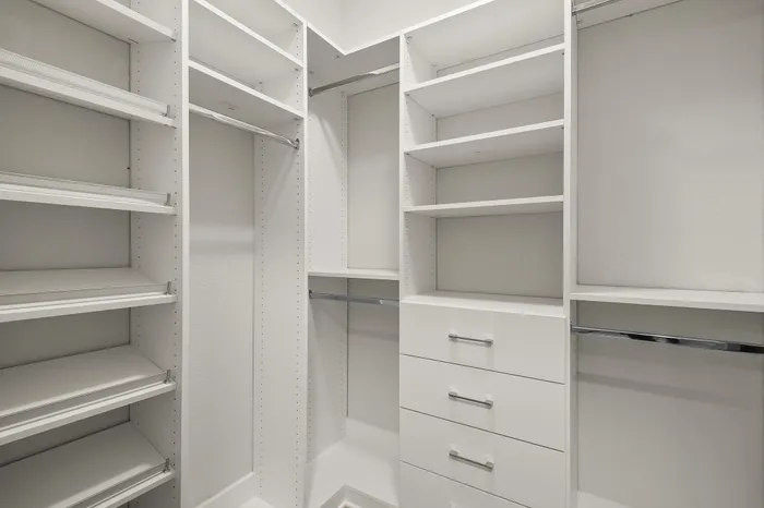 Spacious walk-in closet with sleek white shelving, ample storage solutions, and modern design elements.