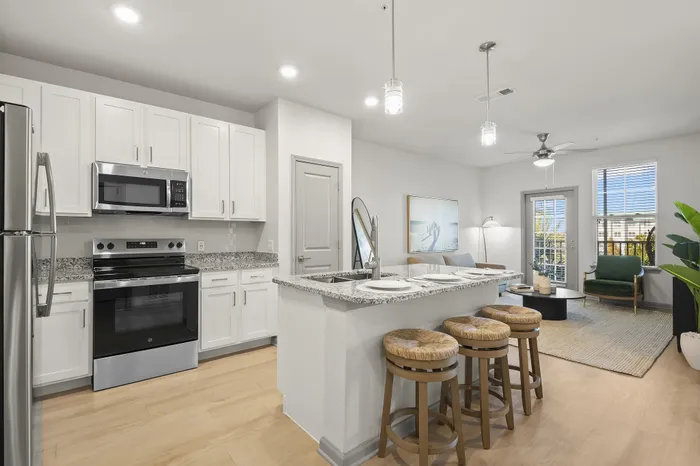 Modern open-concept kitchen and living room with sleek appliances, elegant granite countertops, and cozy seating area.