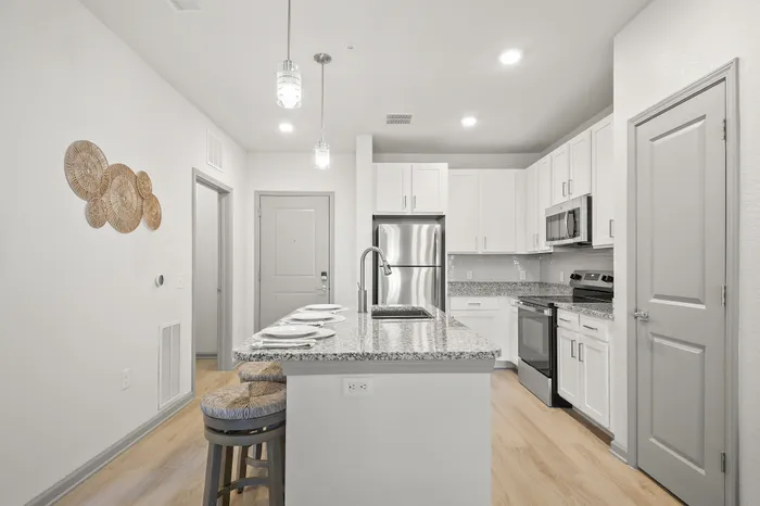Modern kitchen interior with sleek granite countertops, stainless steel appliances, and stylish bar seating. Bright and inviting space perfect for culinary creativity.