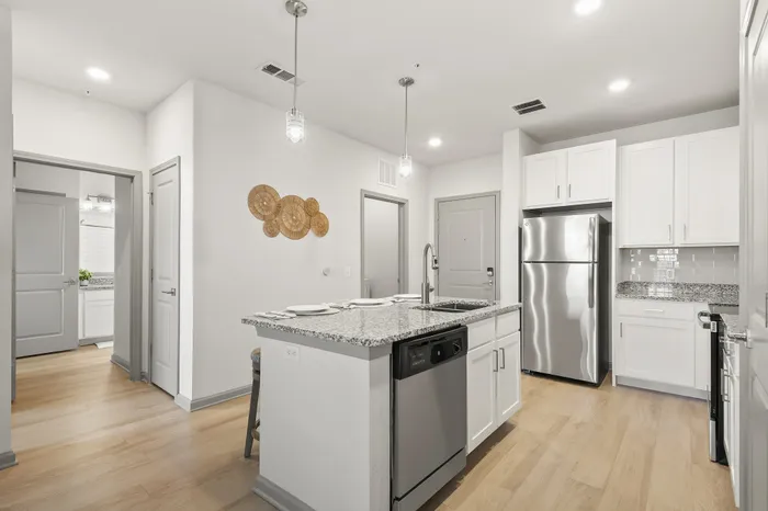 Modern kitchen with sleek granite countertops, stainless steel appliances, and inviting pendant lighting.