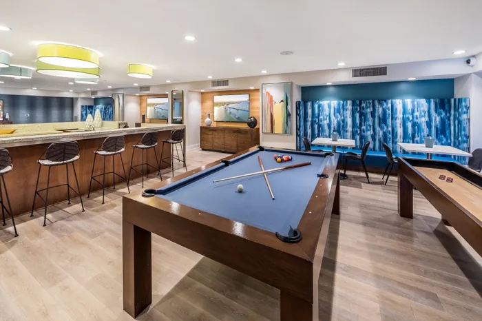 Modern recreational lounge featuring a stylish bar, pool table, and vibrant decor under chic lighting.