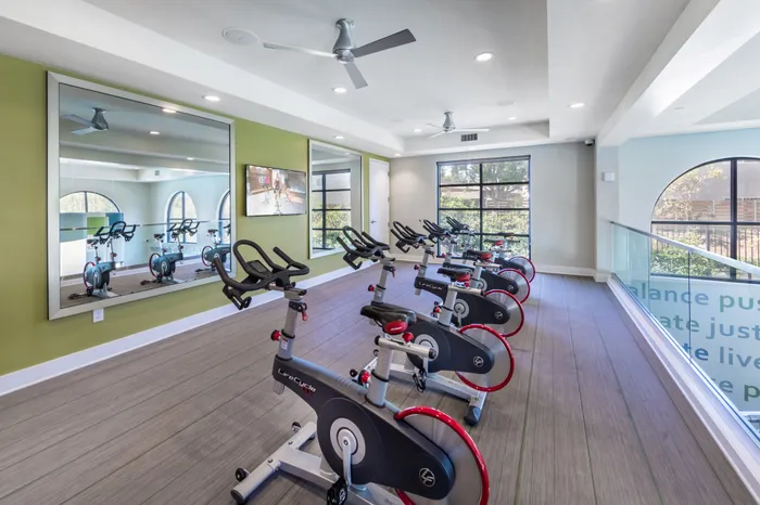 Modern fitness room with sleek exercise bikes and large windows offering natural light and panoramic views.