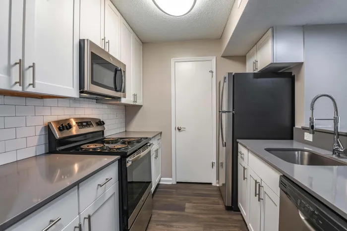 Modern kitchen with sleek stainless steel appliances, elegant white cabinetry, and chic dark countertops, complementing the stylish subway tile backsplash.