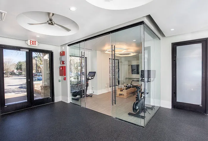 Bright and modern exercise room with sleek glass walls, featuring stationary bikes and natural light for an invigorating workout experience.