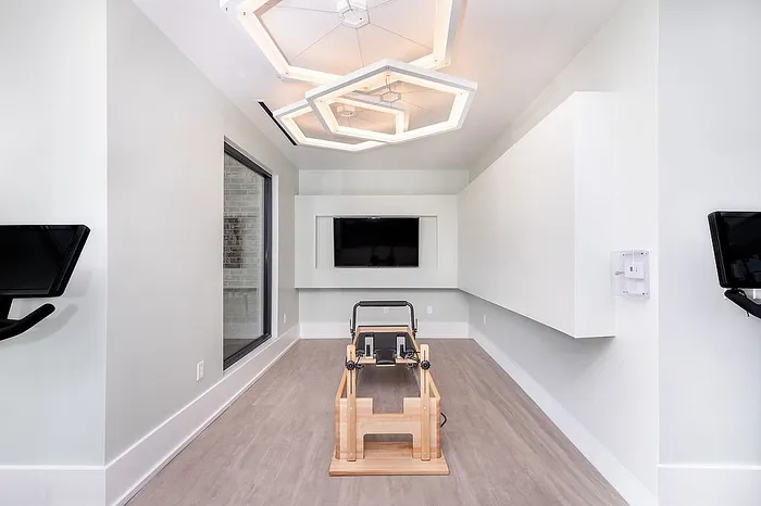 Sleek and modern gym with stylish lighting, featuring workout equipment and a mounted flat-screen TV.