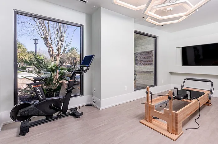 Modern fitness room , featuring a sleek exercise bike and a wooden Pilates reformer, perfect for an invigorating workout.