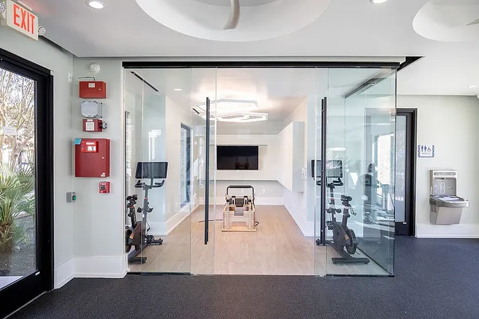 Modern fitness room featuring glass walls, exercise bikes, and sleek design, perfect for a healthy lifestyle.